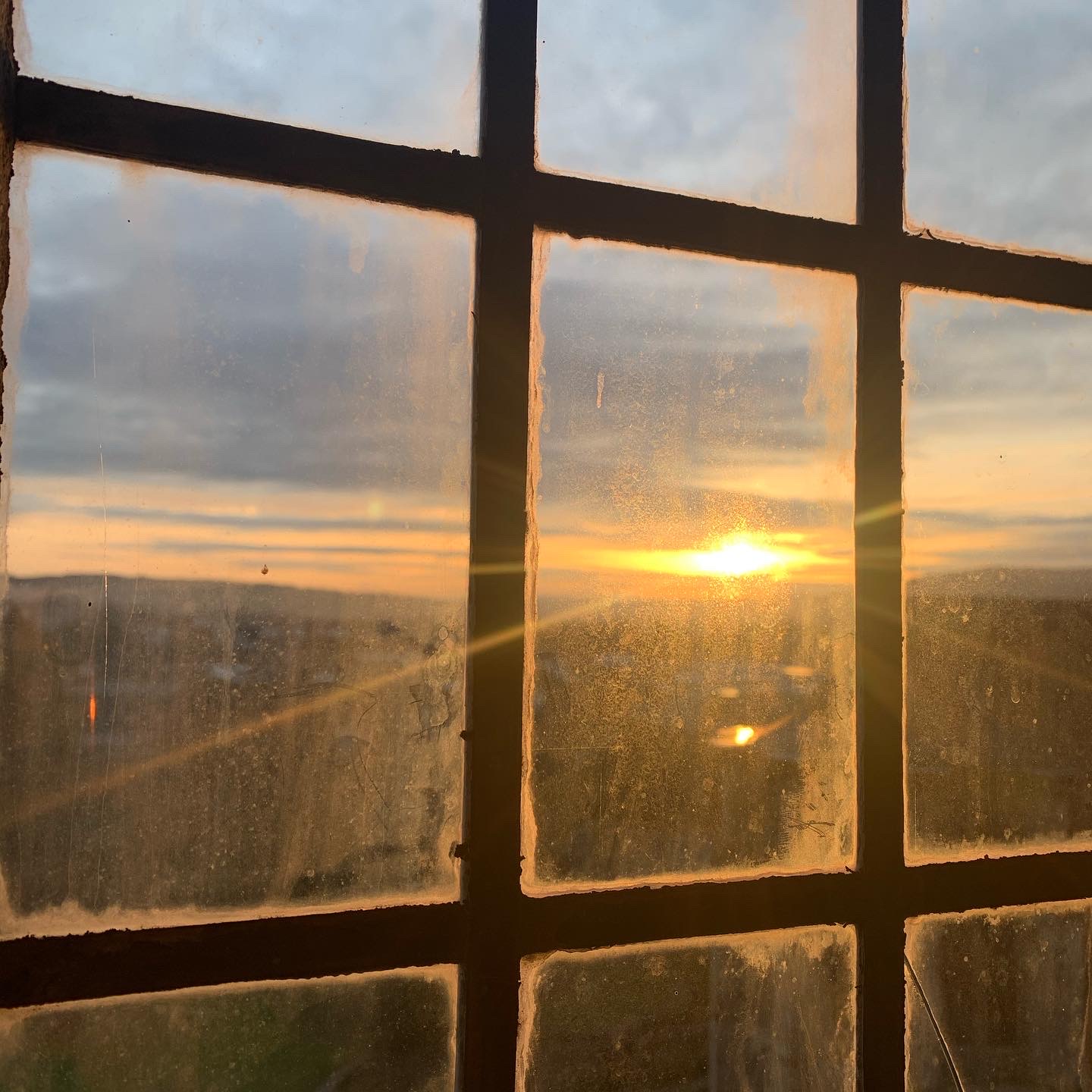 Blick durch ein Fenster auf einen Sonnenuntergang